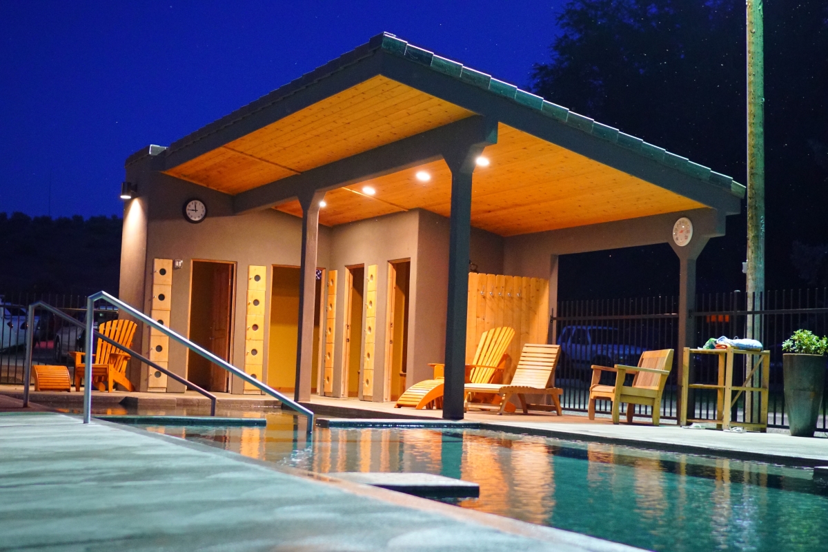 A pool with chairs and a cabana in the background.